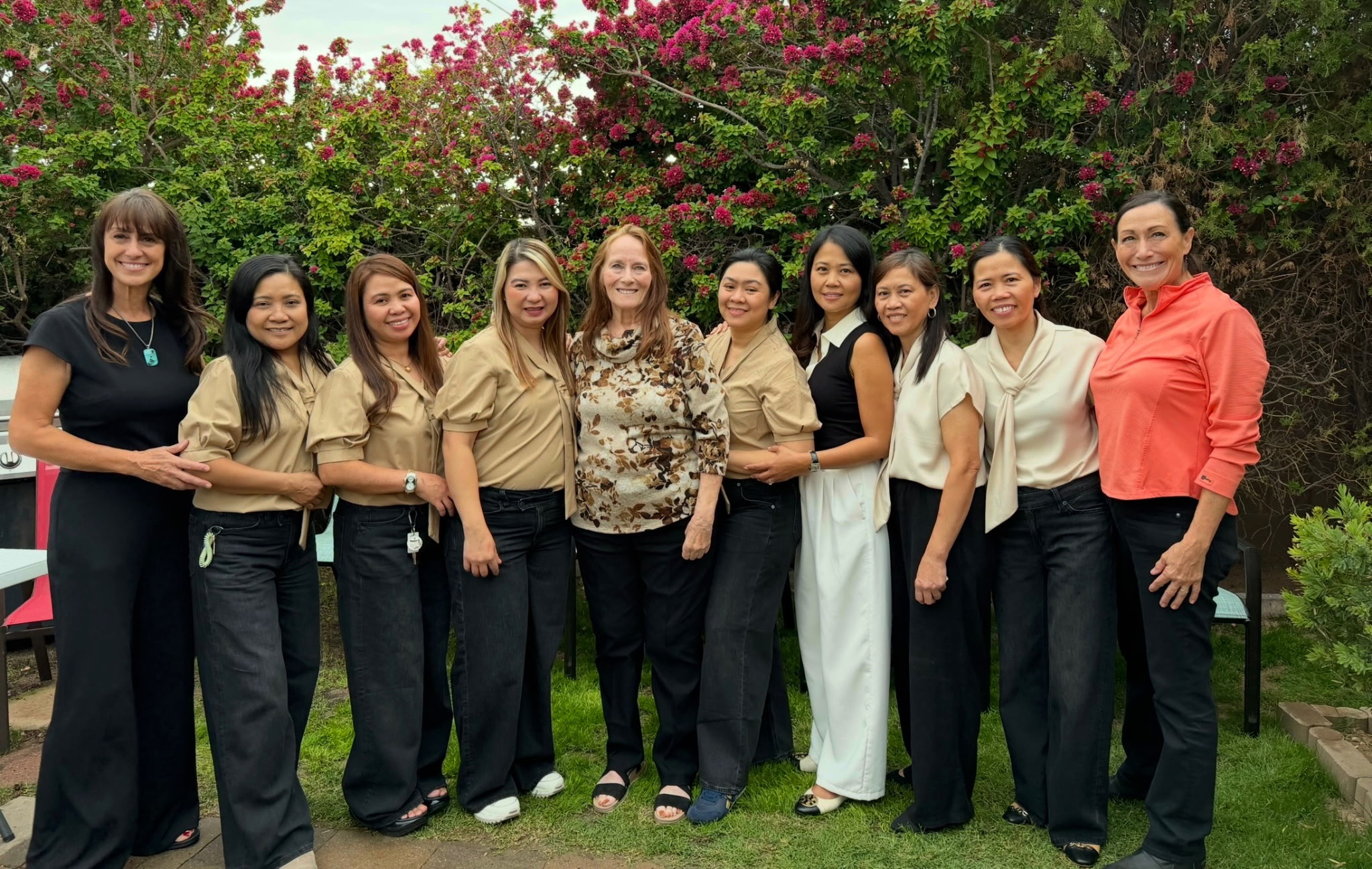 A group of nine women smiling together in the Rivendell garden