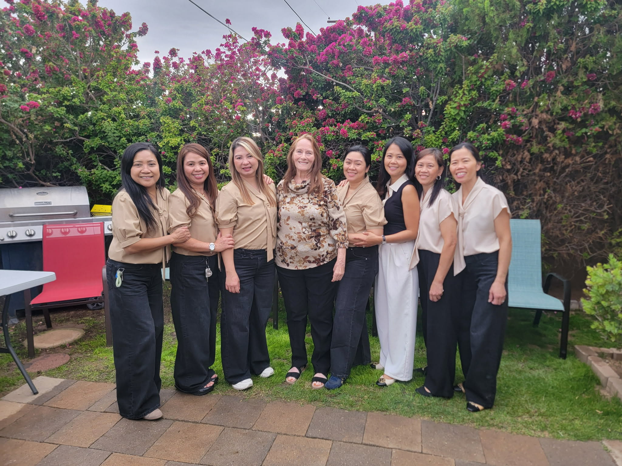 A group of women standing together in the garden beneath flowering trees