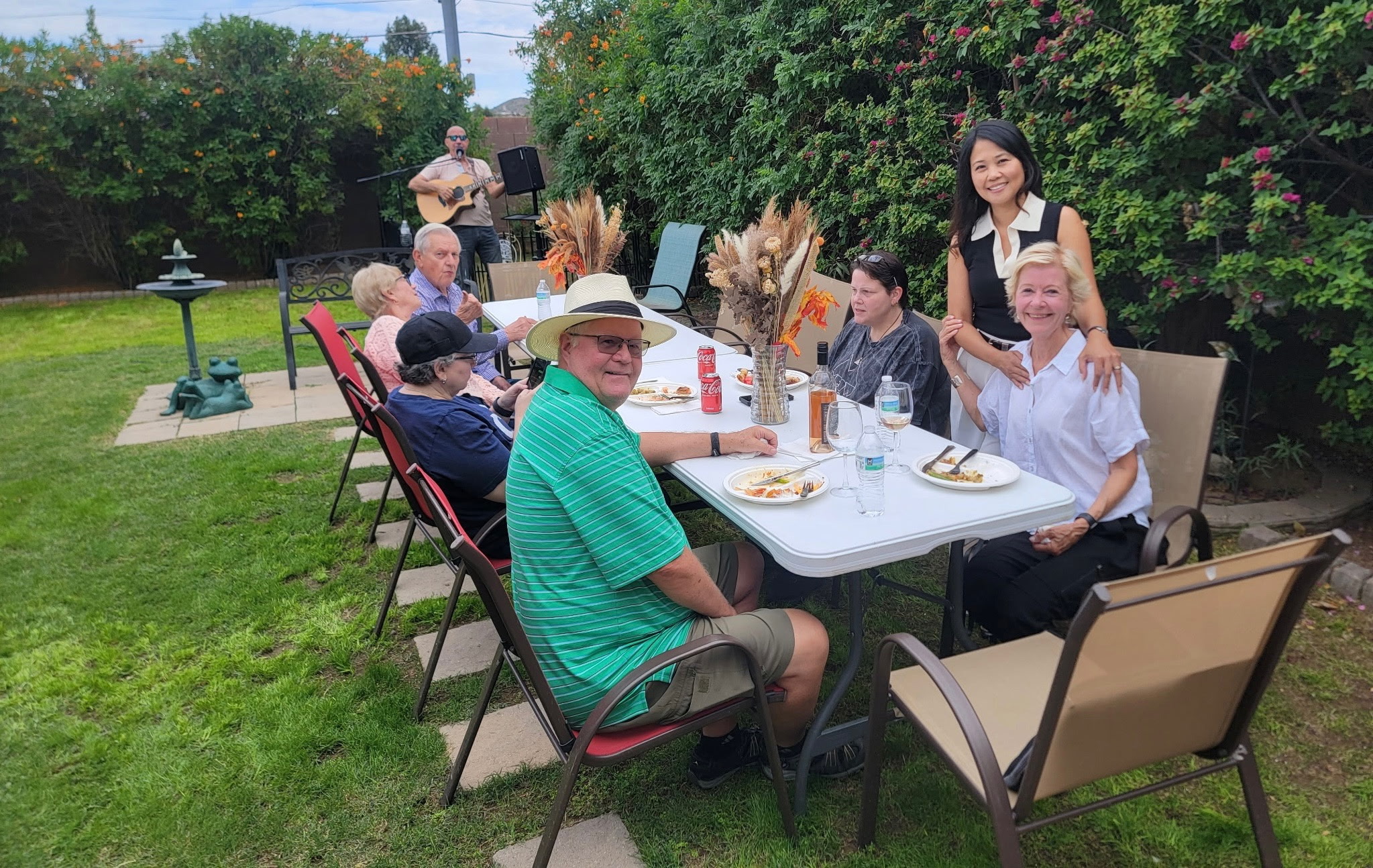 Family and guests enjoying a meal around tables in the garden