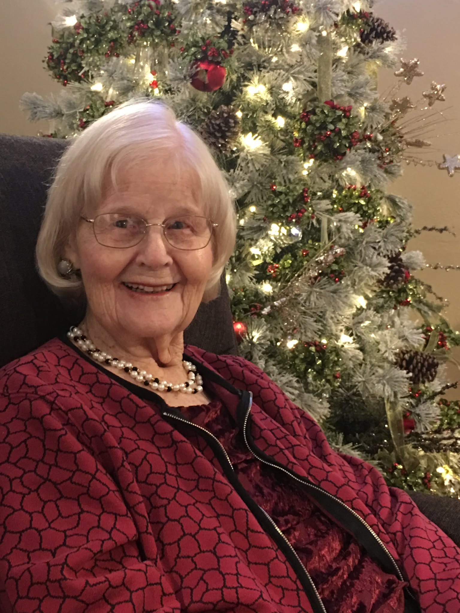 Resident smiling beside the decorated Christmas tree
