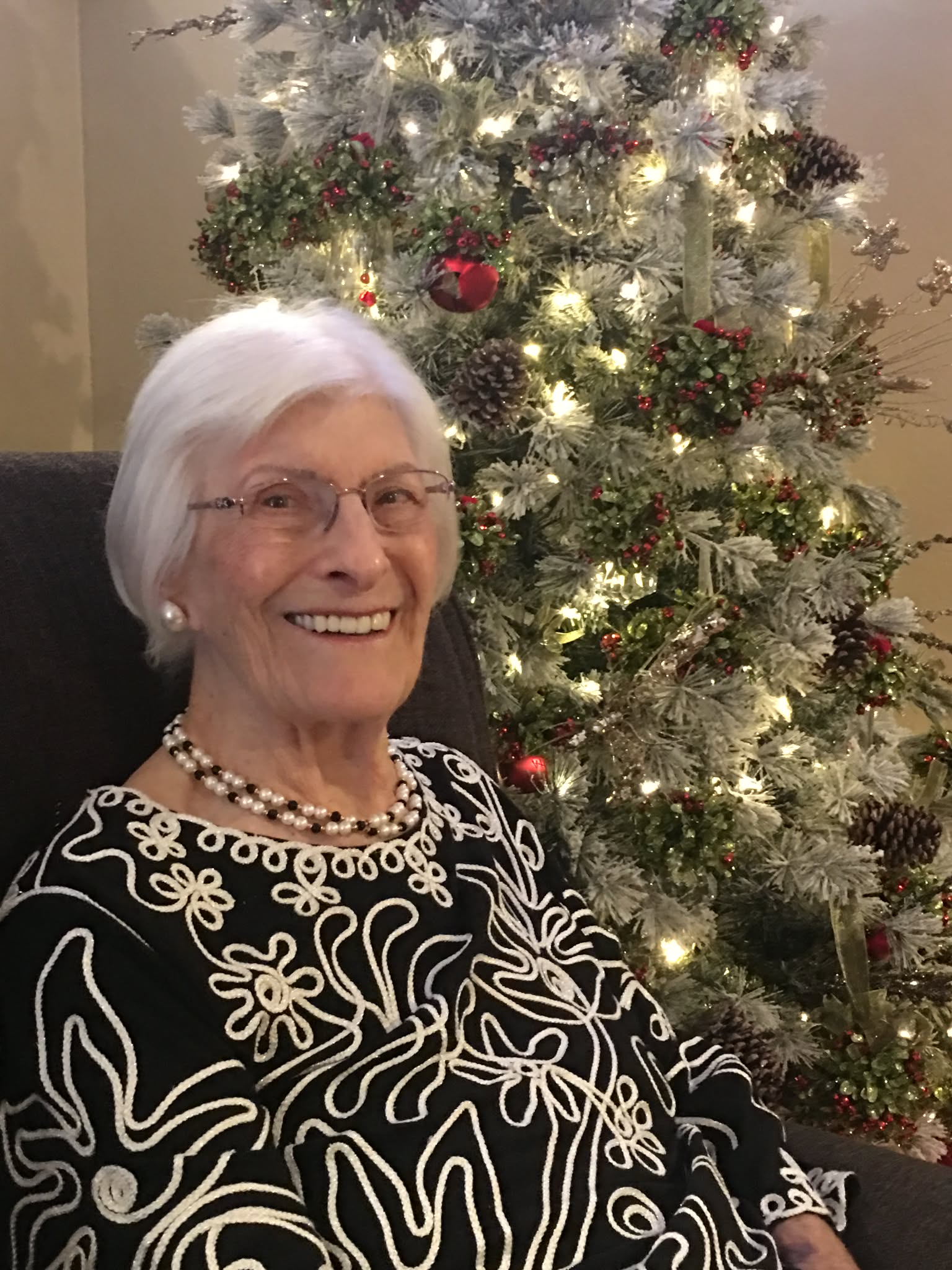Resident smiling beside the decorated Christmas tree