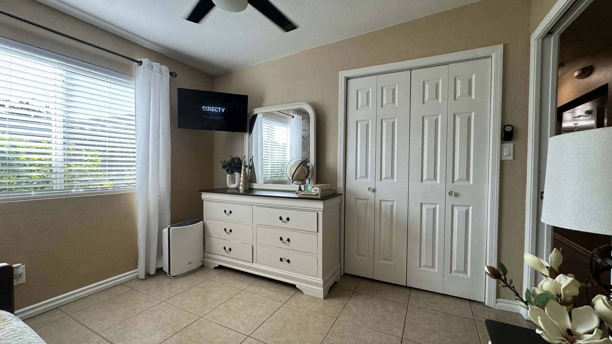 Bedroom dresser and mirror beside a closet and bright window